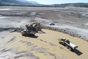 Excavator loading rock trucks from Snake River
